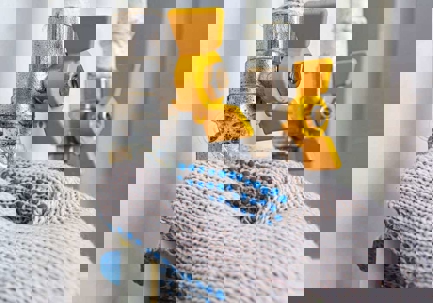 A gloved hand turns a yellow gas shutoff valve