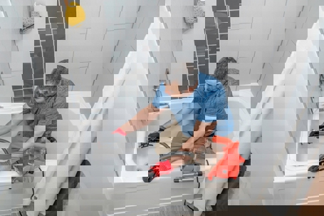 A plumber uses a motorized snake in a bathtub