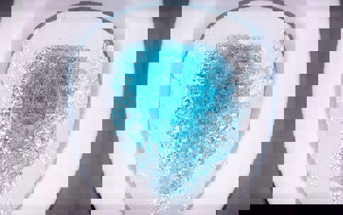 A white toilet bowl is filled with clear, blue-tinted water